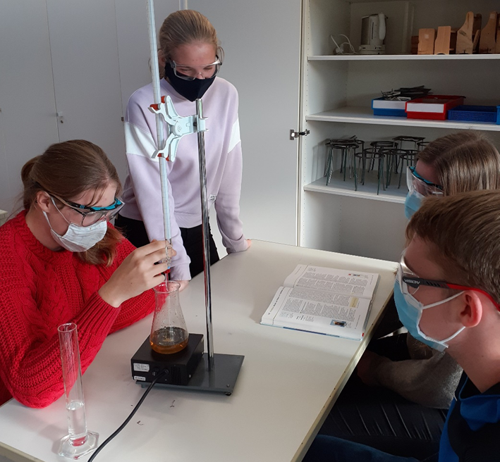 Vier Mitglieder des Chemiekurses bei der Titration von Cola.
