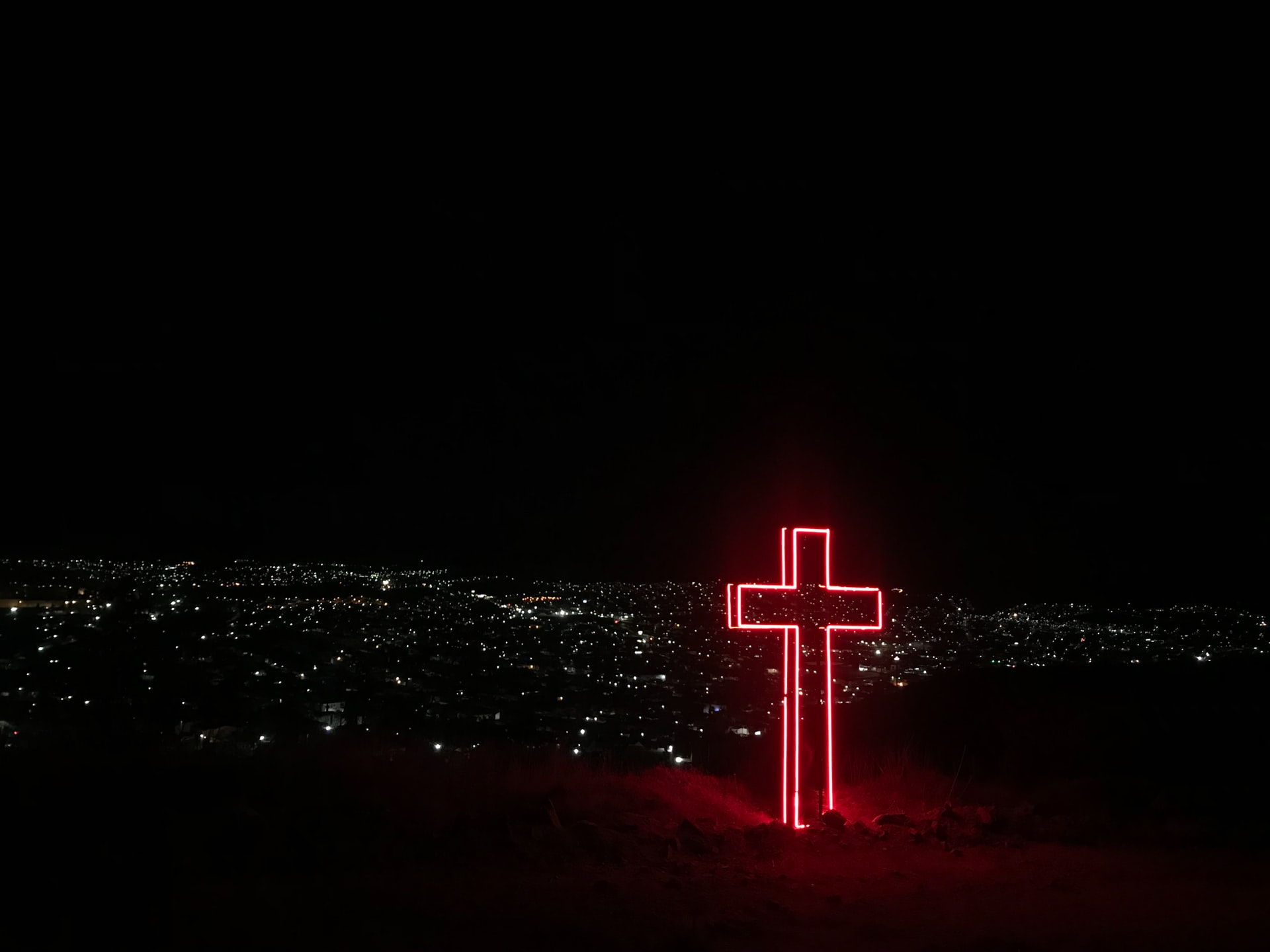 leuchtendes Kreuz in der Nacht - Foto von Diana Vargas (unsplash.com)